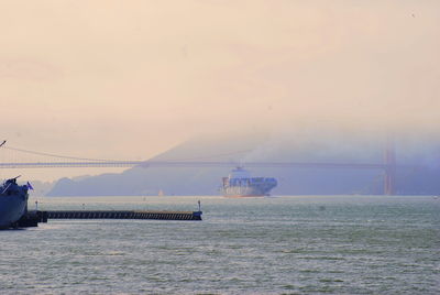 Golden gate bridge over harbor against sky during sunset