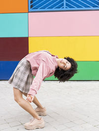 Female dancer bending over backwards while standing on footpath