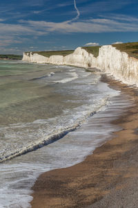 Scenic view of sea by cliff against sky