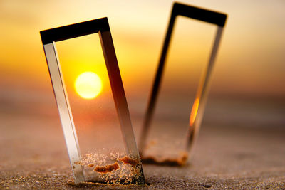 Close-up of glass of water on beach during sunset