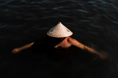 High angle view of man wearing asian style conical hat while swimming in sea