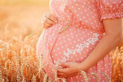 Midsection of woman holding hands on field
