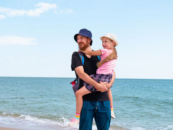 Rear view of man standing at beach against sky