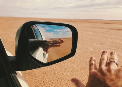 Reflection of hand on side-view mirror of car