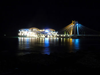 Illuminated bridge over river at night