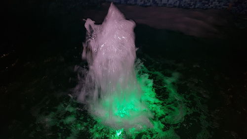 Low angle view of water splashing on rocks at night