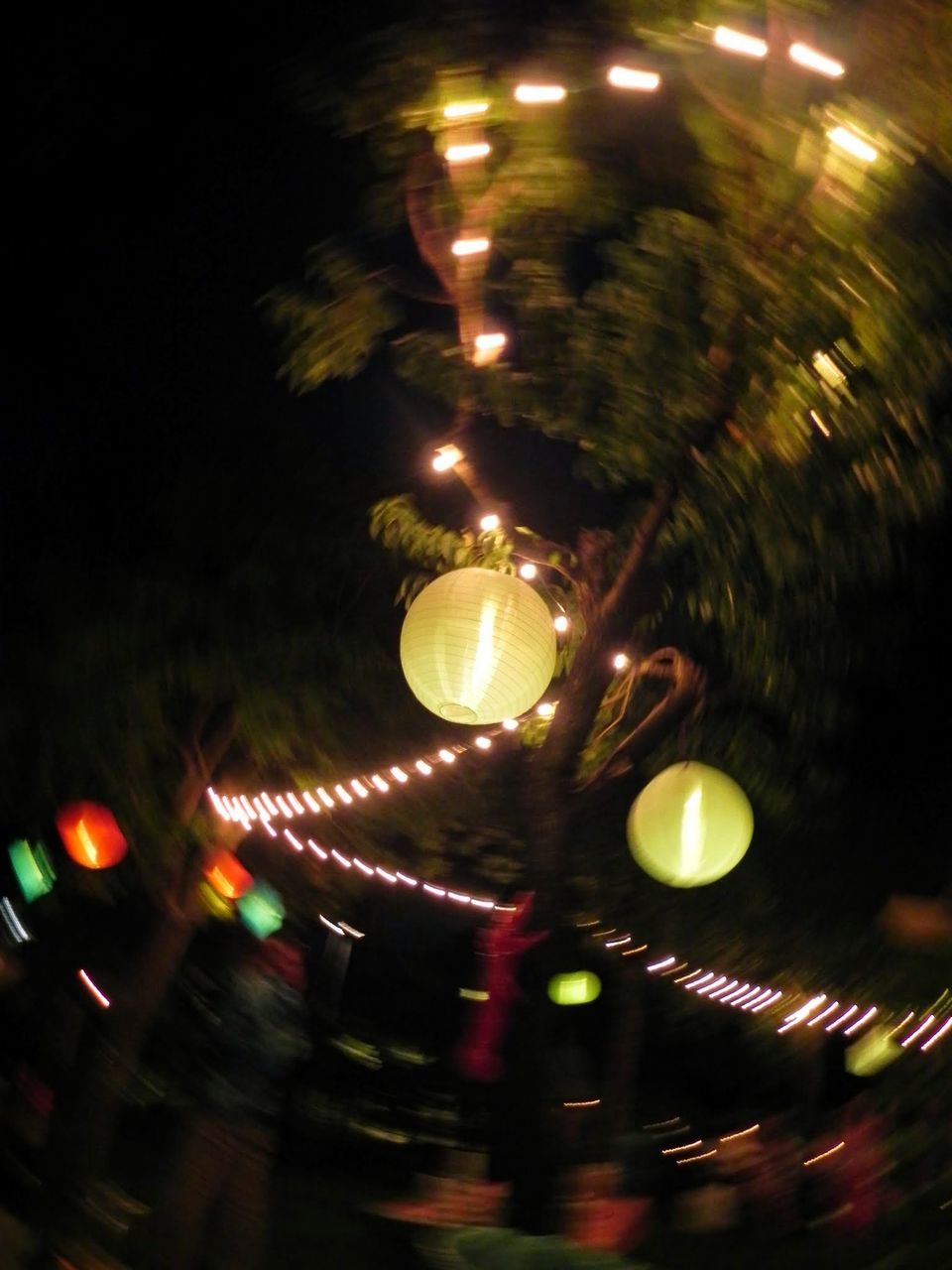 BLURRED MOTION OF ILLUMINATED CAROUSEL IN CITY AT NIGHT