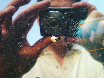 Reflection of man photographing water on camera