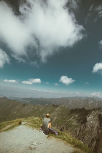 Rear view of woman sitting on mountain