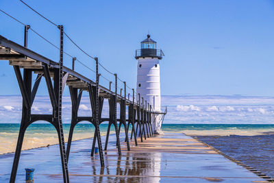 Lighthouse by sea against sky