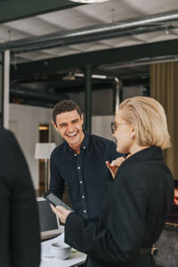 Happy businessman laughing while talking to female colleague at office