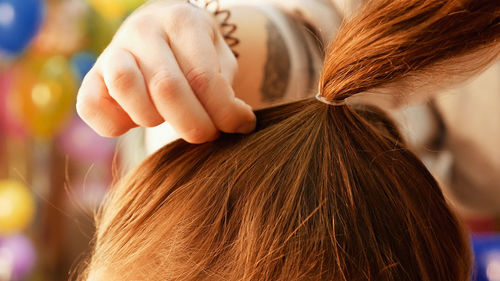 Cropped hands of female hairstylist styling girl hair