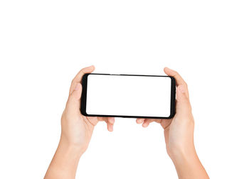 Close-up of hand holding smart phone against white background