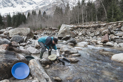 Man and woman standing on rock by stream in forest