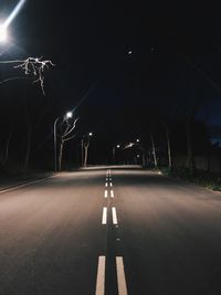 Empty road along illuminated street lights at night