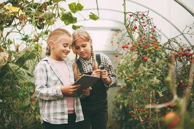 Happy young woman standing against plants