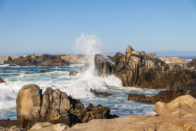 Scenic view of rocks in sea against clear sky