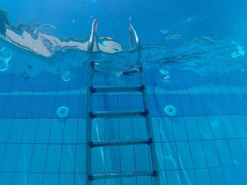 Low angle view of ladder in blue swimming pool