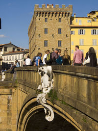 People at ponte santa trinita bridge against buildings