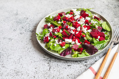 Arugula, beet and cheese salad with pomegranate and dressing on plate