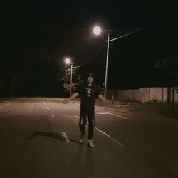 Full length of man standing on illuminated street at night