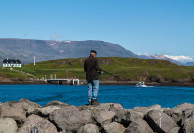Man standing on cliff by sea