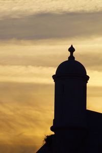 Low angle view of lighthouse against orange sky