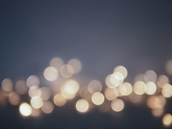 Defocused image of illuminated lights against clear sky