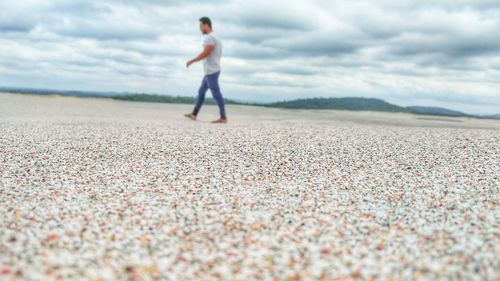 Woman walking on sand against sky