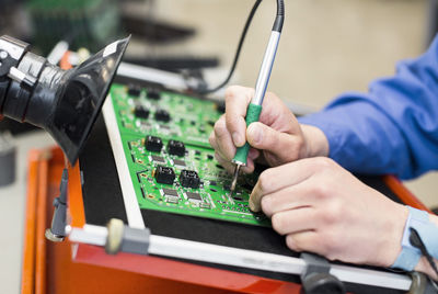 Cropped image of electrician's hand soldering circuit board