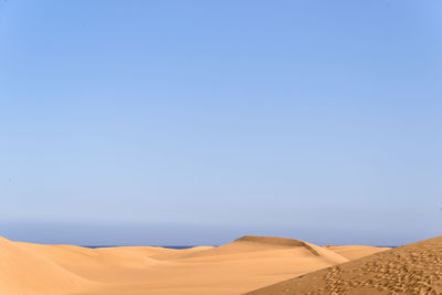 Scenic view of desert against clear blue sky