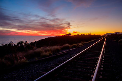 Railroad tracks against sky during sunset