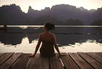 Rear view of woman sitting on lakeshore