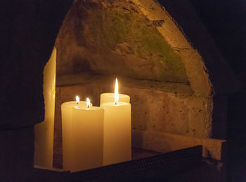 Close-up of illuminated tea light candles on wall