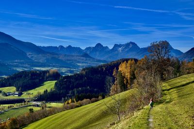 Scenic view of landscape and mountains against blue sky in autumn