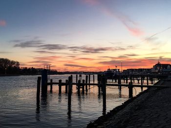 Silhouette pier on river against sky during sunset
