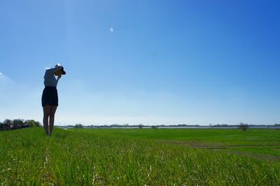 Woman standing on field against clear blue sky