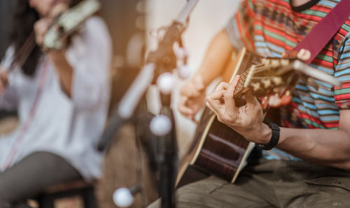 Midsection of man playing guitar at music concert