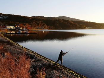 Side view of a man fishing at calm lake