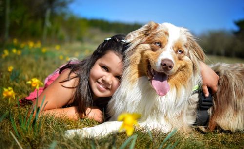 Portrait of cute girl with dog lying on grass