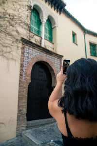 Midsection of person photographing against building