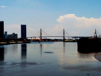 Bridge over river against cloudy sky