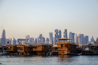 Traditional wooden dhows in doha, qatar. the skyline of the modern and high-rising city of doha.