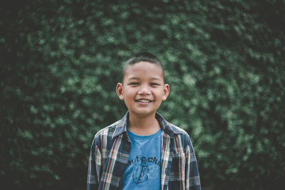 Portrait of smiling boy standing against plants