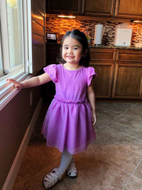 Full length portrait of cute girl standing in kitchen at home