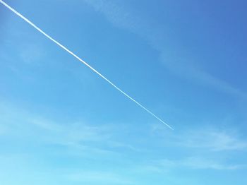 Low angle view of vapor trail in blue sky