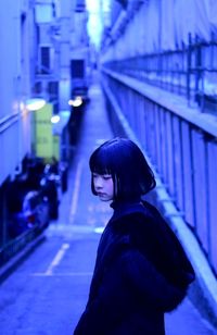 Side view of woman standing against illuminated city at night