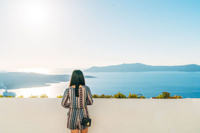 Rear view of woman looking at sea against clear sky