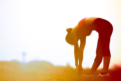 Side view of silhouette woman standing on field against sky