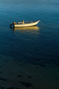 An old motor boat is anchored in the bay at sunset